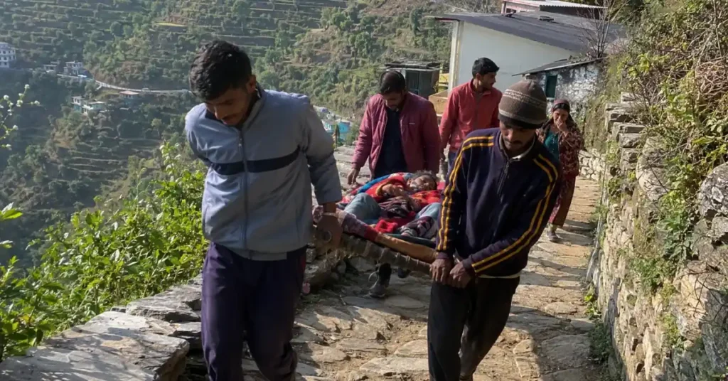 पहाड़ी क्षेत्र में बीमार व्यक्ति को स्ट्रेचर के सहारे अस्पताल तक ले जाते ग्रामीण