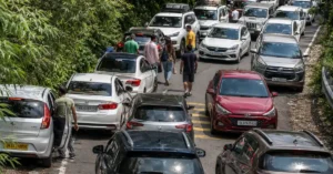 Heavy tourist traffic on a forest-side road near Rishikesh during peak travel season.