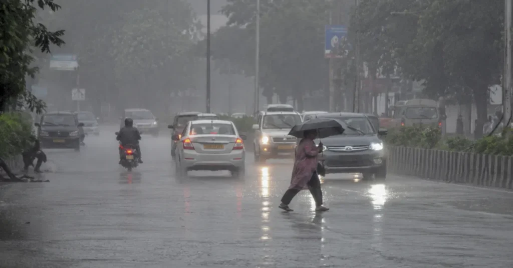 उत्तराखंड में भारी बारिश के दौरान शहर की सड़क पर वाहन और पैदल यात्री