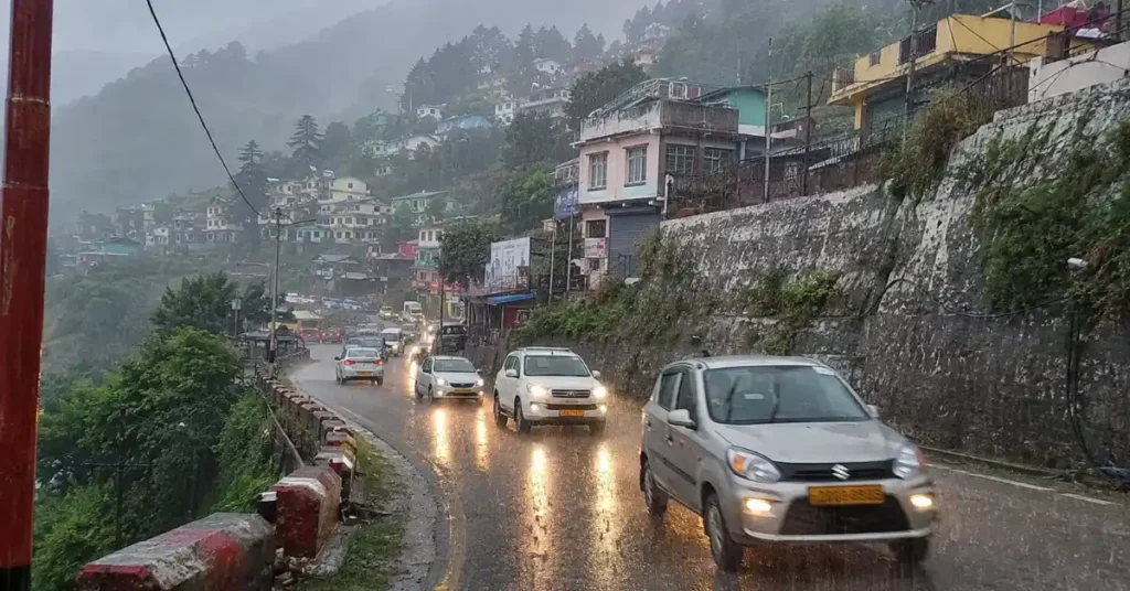 Vehicles moving on a rain-soaked hill road in Uttarakhand during monsoon conditions.