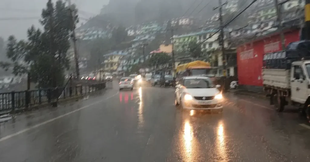 बारिश के दौरान उत्तराखंड के एक पहाड़ी कस्बे में सड़क पर चल रहे वाहन