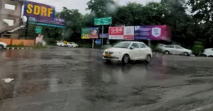 देहरादून में बारिश के दौरान भीगे सड़क मार्ग पर वाहनों की आवाजाही