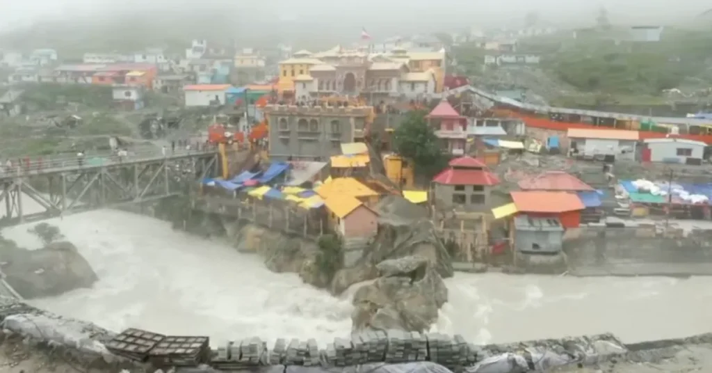 The Badrinath temple area beside the fast-flowing Alaknanda River during continuous monsoon rainfall in Uttarakhand.