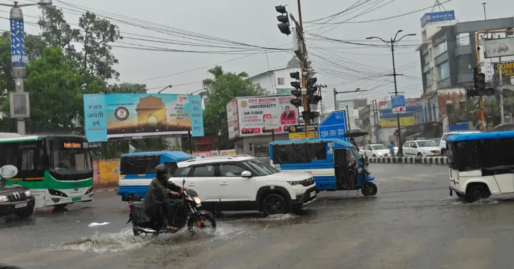 Heavy rainfall causes waterlogging and slow-moving traffic at a road intersection in Dehradun.