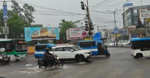 Heavy rainfall causes waterlogging and slow-moving traffic at a road intersection in Dehradun.