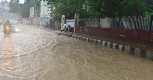Waterlogged road in Dehradun after heavy rainfall as vehicles move through flooded streets.