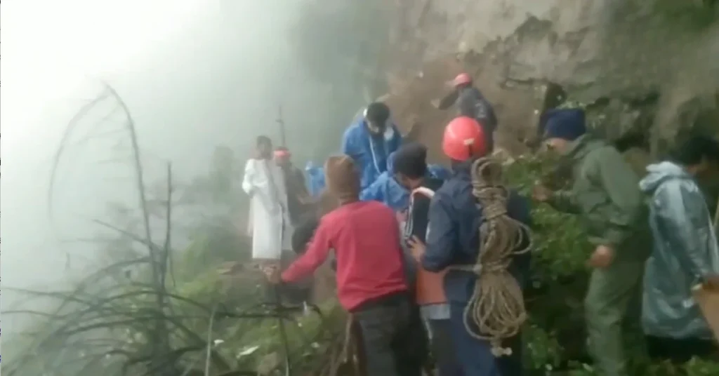 Rescue personnel and officials assist pilgrims along a landslide-affected section of the Kedarnath foot route during monsoon conditions.