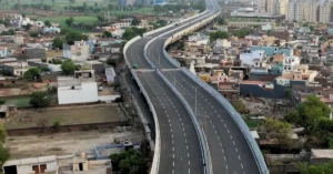 An elevated multi-lane urban roadway passing through a densely populated city area, illustrating the concept of an elevated transport corridor.