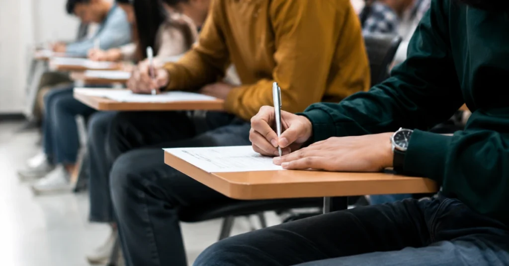 Candidates appear for the Uttarakhand Nursing Officer recruitment written examination at a government examination centre.