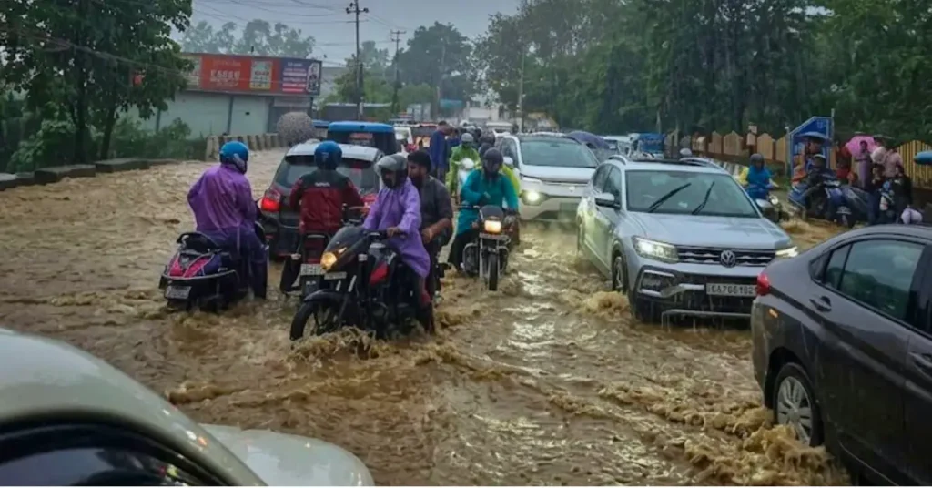 Vehicles and commuters move through a waterlogged road during heavy rainfall in Uttarakhand.