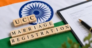 Wooden letter tiles spelling “UCC Marriage Registration” placed on the Indian tricolour with an Ashoka Chakra, alongside a registration document and pen.