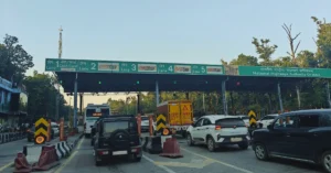 Original photograph of Doiwala toll plaza in Dehradun, Uttarakhand, showing cars, commercial vehicles and multiple toll lanes beneath the NHAI canopy.