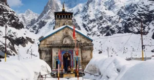 Kedarnath Temple in Uttarakhand surrounded by deep snowbanks, with snow-covered Himalayan mountains and the historic stone temple visible in the centre.