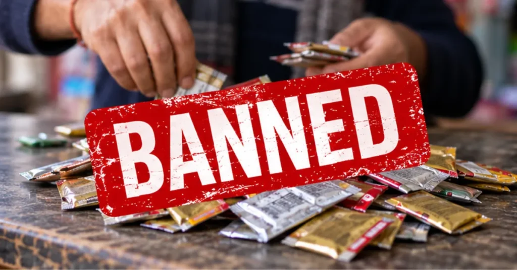 Editorial image showing small packaged sachets on a shop counter with a prominent red BANNED graphic, representing Uttarakhand's ban on gutkha and tobacco-nicotine-containing pan masala.