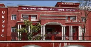 Front view of the UKSSSC office building in Uttarakhand, showing the red-brick facade, entrance and commission signage, related to the वन आरक्षी recruitment proposal for 189 posts.